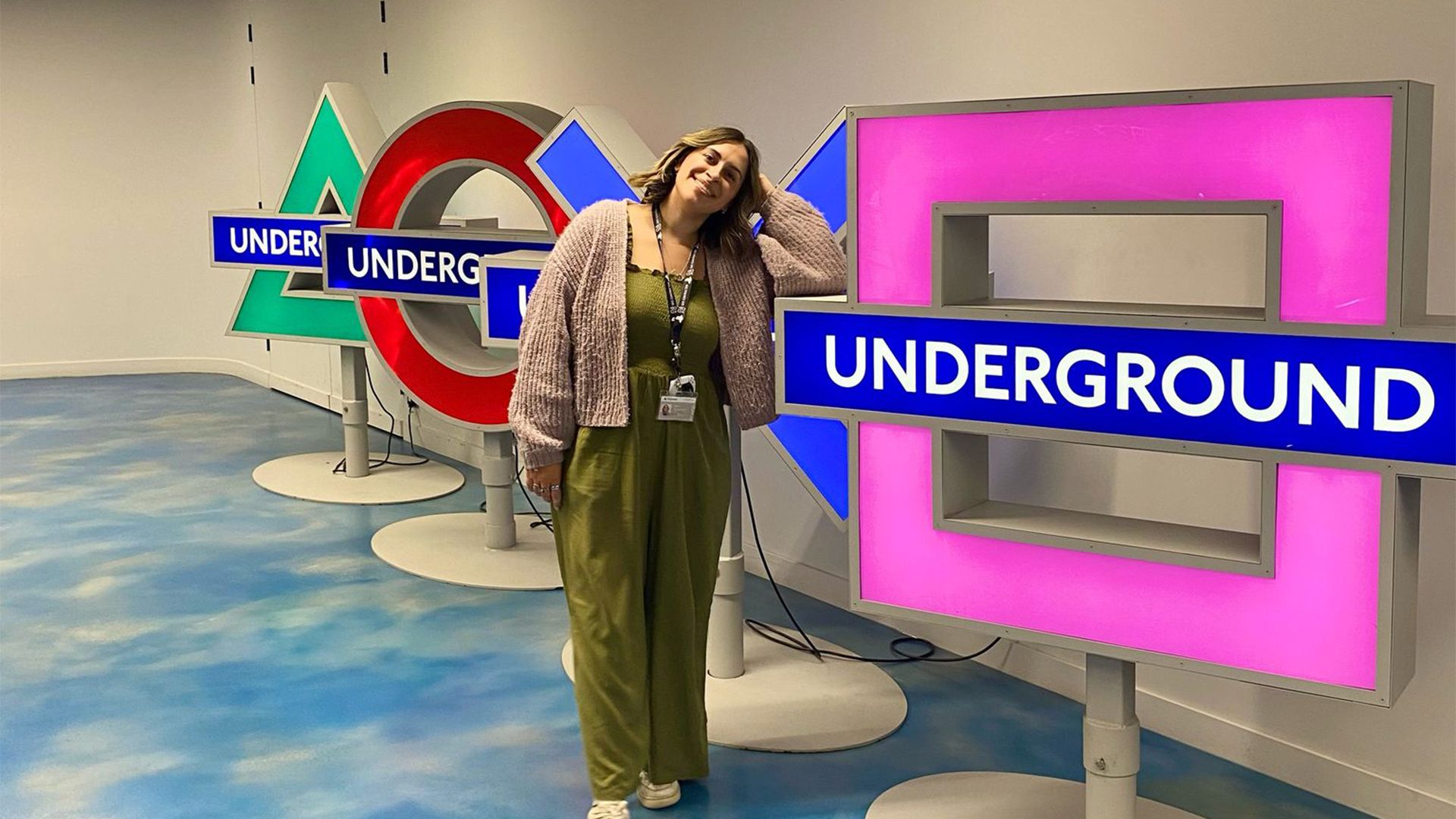 Enya in front of the PlayStation shapes logo (pink square, blue cross, red circle, green triangle)