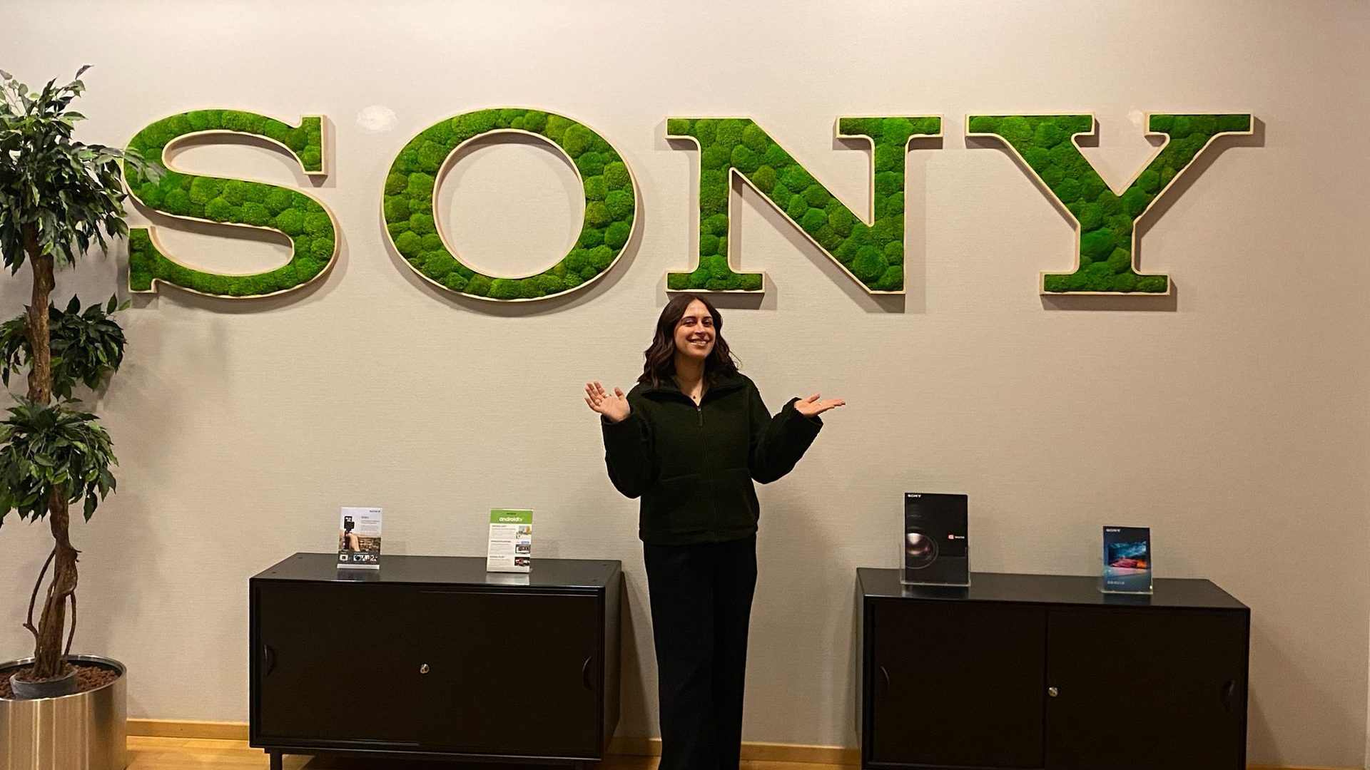 Enya in front of a white wall with a green SONY logo.
