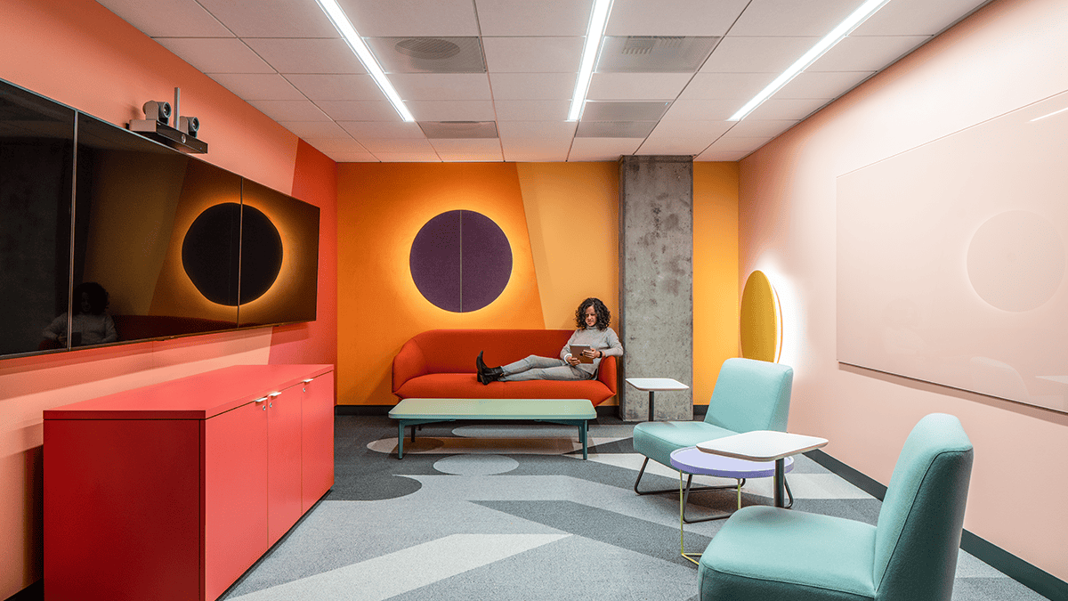 Empty employee breakroom that's decorated in mid century modern design and very bright colors such as red and orange walls and green furniture.