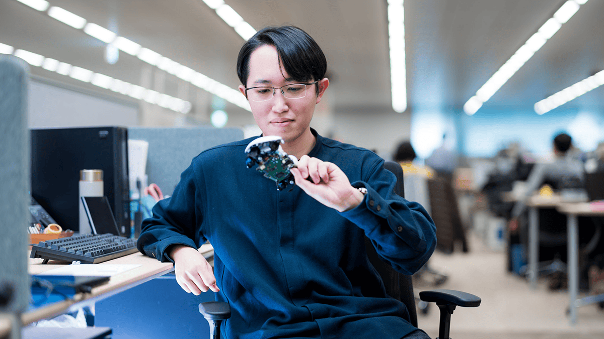 Sony engineer looking at a broken down DualSense controller at his desk.